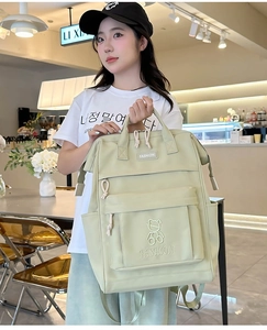 Close-up of light green nylon school backpack with cute bear embroidery and fashion label