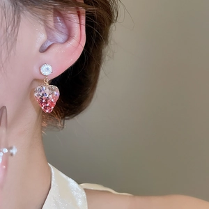Detail of pink resin strawberry earring with sparkling sequins on a female model