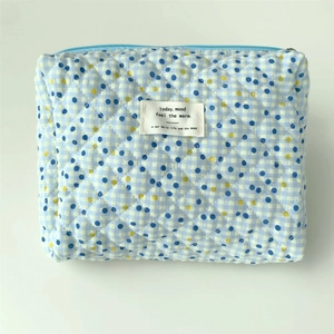 Detail of blue and white checkered quilted cotton bag with light blue zipper and label