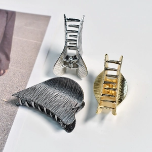 Three medium metal hair claw clips in gold silver and dark grey with brushed texture