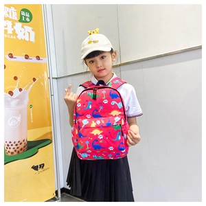 Detailed view of red children's backpack featuring colorful cartoon dinosaur prints