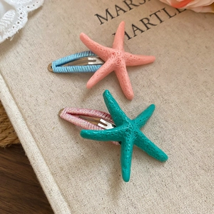 Detailed view of starfish hair clips in pink and teal resin with braided fabric bases