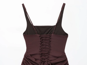 Detail of burgundy backless dress featuring lace-up straps and ruched textured fabric