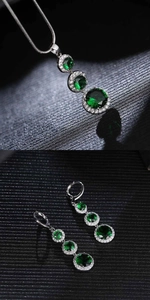 Detailed view of silver necklace and earrings set with green round gemstones and diamonds