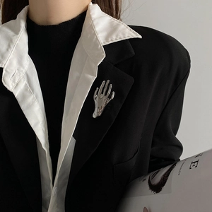 Close-up of a silver palm brooch in liquid metal style on a black suit lapel