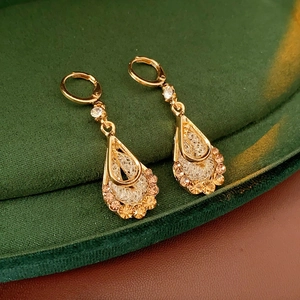 Detailed macro view of gold-finished drop earrings with hollow mesh and zirconia accents