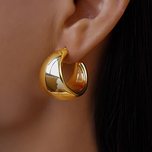 Close-up of chunky gold hoop earrings with a high-polished finish on model's ear
