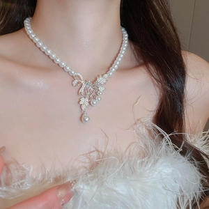 Detail of elegant pearl necklace with rhinestone bow and flower pendant on a model