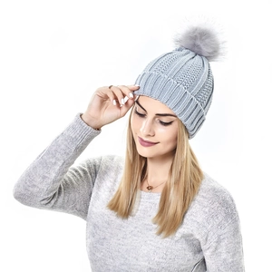 Close-up of grey knit beanie featuring a large faux fur pompom and thick ribbed texture