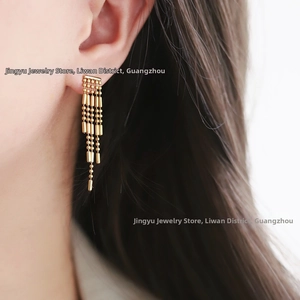 Detailed view of long gold tassel earrings with cascading beads on a female model