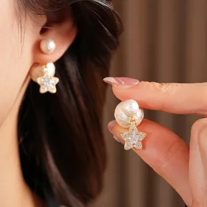 18K gold-plated star earrings with pearls and cubic zirconia on a model's ear