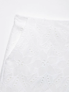 Macro del tessuto ricamato bianco con dettagli floreali traforati su pantaloncini