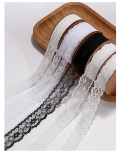 Close-up of vintage white and black lace ribbons with intricate floral patterns on a tray
