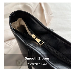 Close-up of smooth golden metal zipper and fine leather texture on black tote bag