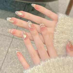 Detailed view of almond-shaped press-on nails with pearl chains and gold foil accents