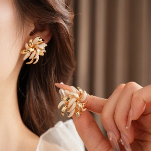 Detail of vintage gold-plated daisy earrings with white enamel petals worn by a model