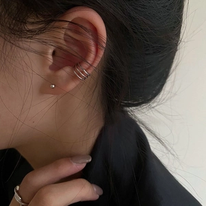 Detail of silver multi-layered ear cuff and ball stud earring on model's ear