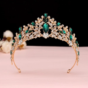 Close-up of golden Baroque crown featuring emerald gems and shimmering white rhinestones
