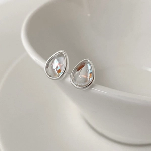 Macro shot of silver teardrop earrings with clear multi-faceted crystals on ceramic edge