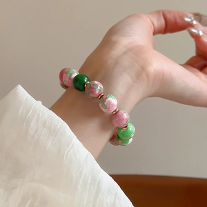 Vintage floral ceramic beads stretch bracelet with gold plating shown on female wrist