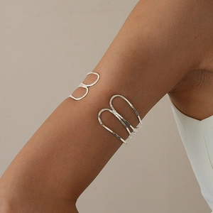 Detail of minimalist silver multi-layer crossover arm cuff on model's upper arm