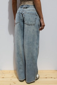 Detail of high-waist wide-leg jeans showing washed denim texture and back pocket design