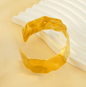 Macro view of 18K gold-plated cuff bracelet featuring a unique hammered wavy texture