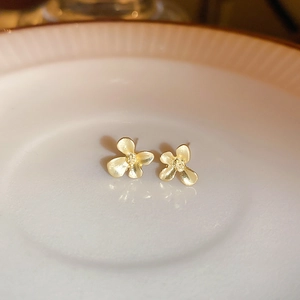 Gros plan de boucles d'oreilles dorées en forme de fleur sur un plateau en céramique blanc