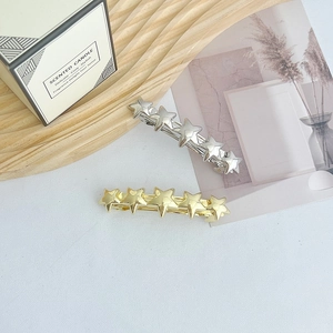 Detail view of gold and silver metallic star hair clips on elegant home decor background