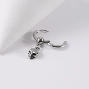 Detailed close-up of a vintage silver stainless steel hoop earring with a 3D skull pendant