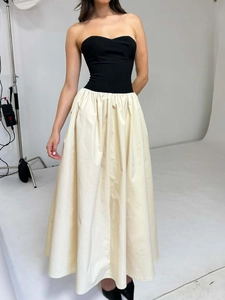 Détail d'une robe bustier chic avec corsage noir et jupe trapèze en blanc cassé