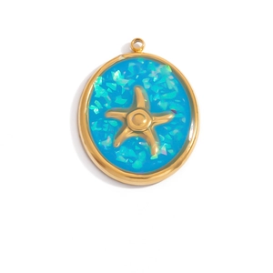 Detailed macro of a circular gold pendant with a blue glitter starfish ocean design