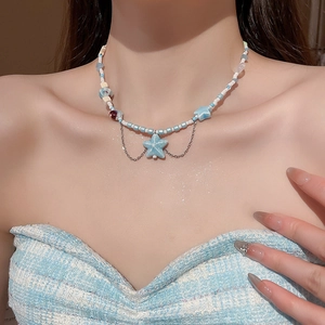 Detail of seashell and starfish pendant necklace with blue beads on female model neck