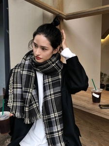 Détail d'une écharpe à carreaux douce avec franges portée par un mannequin en extérieur