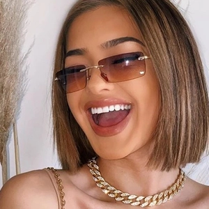 Close-up of rimless square sunglasses and a shimmering crystal Cuban chain necklace