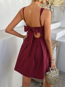 Detail of burgundy backless summer dress with elegant bow tie and pleated skirt