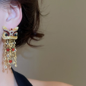 Vue macro des boucles d'oreilles Lion de Danse avec pompons dorés et pierres zircons