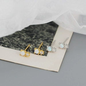 Close-up of gold and silver S925 earrings with round white opal and tiny zircon stone