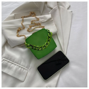 Detail of green square handbag with chunky acrylic handle and gold chain strap