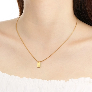 Detailed shot of golden snake chain necklace with rectangular H initial pendant on a model