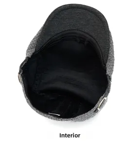 Detail of grey knitted newsboy cap featuring black quilted lining and metal side buckles