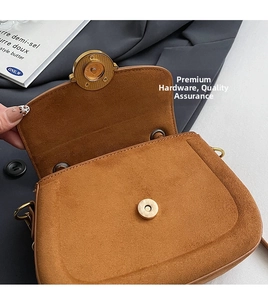 Close-up of golden magnetic clasp and premium suede texture on retro brown saddle bag