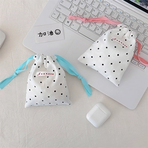 Close-up of polka dot drawstring storage bags set with woven labels on a white laptop