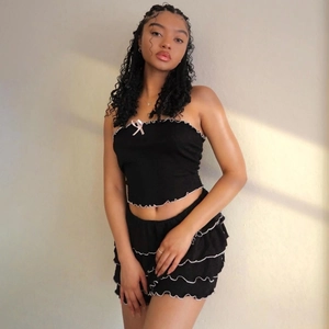 Ensemble chic noir avec haut bustier, short à volants et petit nœud rose pour l'été