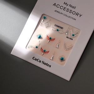 Detail of luxury 3D turquoise nail charms with golden geometric frames in a gift box