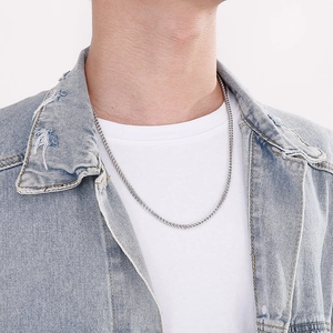 Collier chaîne tressée en argent sur cou de mannequin avec veste en jean