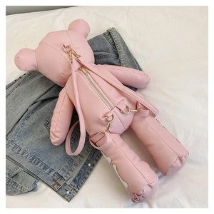 Detailed view of pink leather bear backpack featuring litchi texture and metal hooks