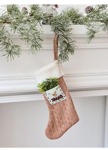 Detail of a brown knitted Christmas stocking with plush trim and XMAS pocket decor