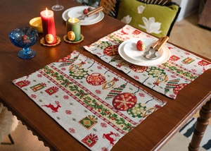 Close-up of woven Christmas table runner with reindeer and festive ornaments on wood