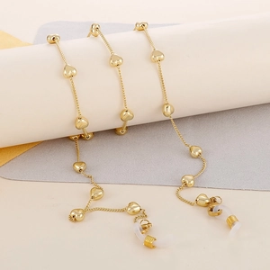 Detailed shot of golden stainless steel glasses chain with heart charms and clear rubber loops